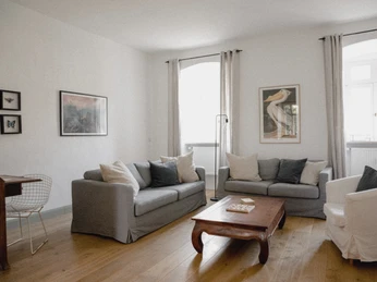 RDF_MG_4713.jpg Wohnzimmer mit zwei grauen Sofas, einem Sessel, Holztisch, Kunst an den Wänden, hellem Holzfußboden.