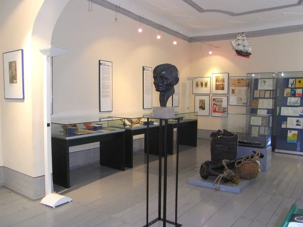 Intérieur d'un musée avec une sculpture au premier plan, des vitrines avec des objets exposés sur les murs.