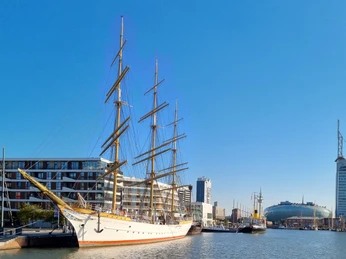 Havenwelten (c) Tanja Tiedemann_Erlebnis Bremerhaven_Ausschnitt.jpg Segelschiff im Hafen von Bremerhaven vor modernen Gebäuden und dem markanten Sail City Hotel.