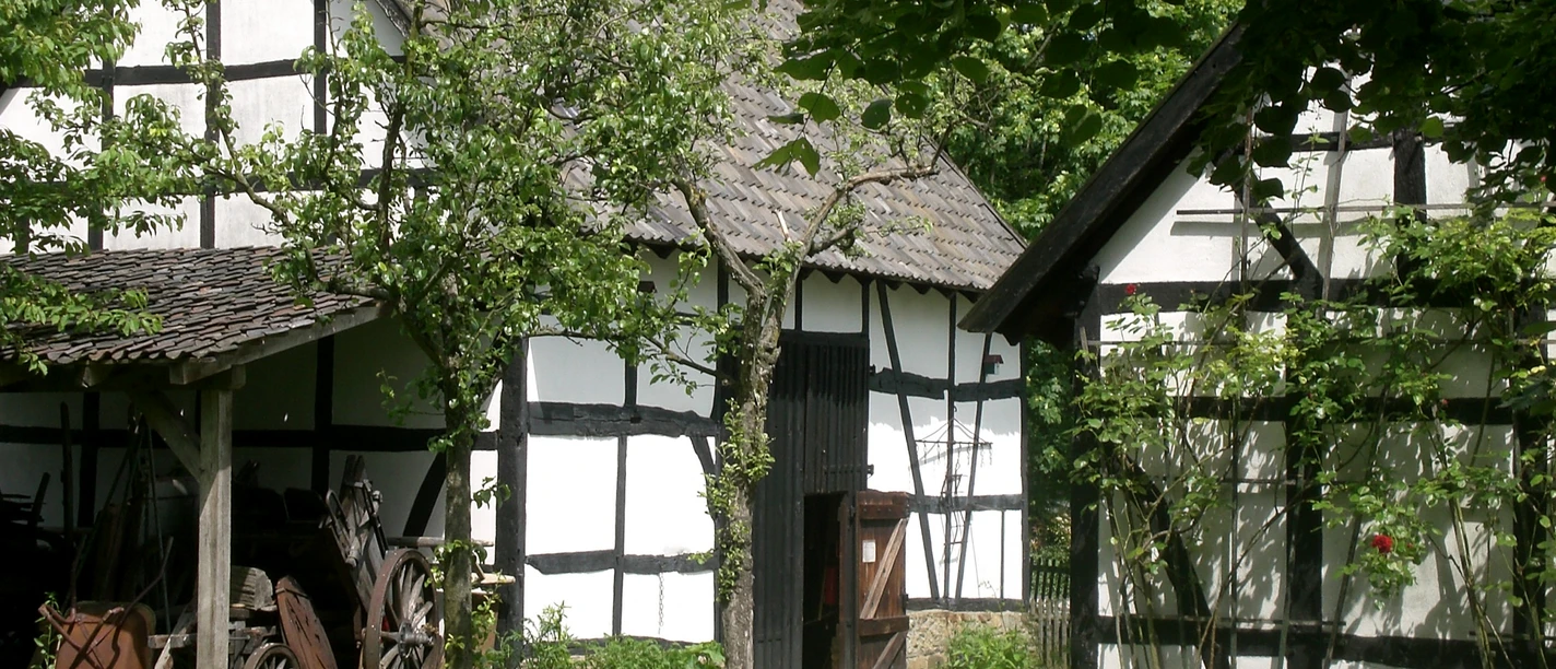 Bergisches Museum für Bergbau Handwerk & Gewerbe Fachwerkhäuser in grüner Umgebung mit alten landwirtschaftlichen Gerätschaften im Freilichtmuseum.