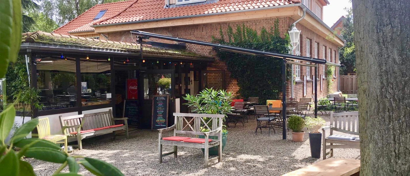 Eiscafé Bäk.jpg Blick vom Innenhof auf Sitzgelegenheiten vor dem Haus mit Tischen und Stühlen