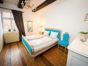 Schlafzimmer Ein elegant eingerichtetes Schlafzimmer mit einem barocken Doppelbett und passenden blauen Akzenten.