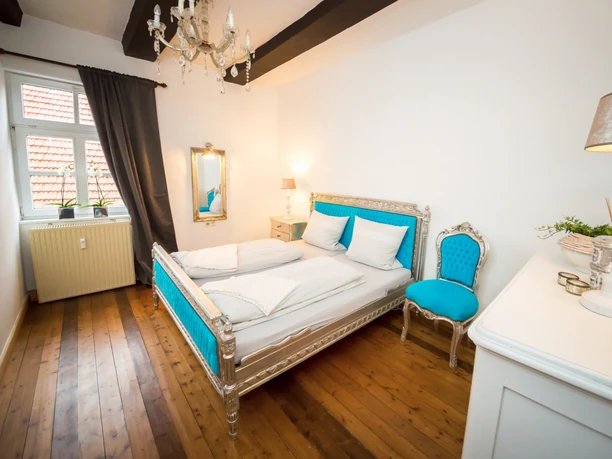 Schlafzimmer Ein elegant eingerichtetes Schlafzimmer mit einem barocken Doppelbett und passenden blauen Akzenten.