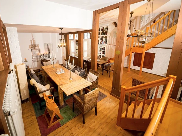 Essbereich Ein Esszimmer mit Holzboden, einem langen Holztisch, Korbstühlen und Kerzenleuchtern auf dem Tisch.