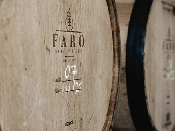 FARO Whisky Destillery_Whiskyfass.jpg Ein großes Holzfass mit der Aufschrift ‚FARO‘ steht in einem Lagerraum.