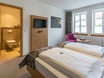 Doppelzimmer Modernes Doppelzimmer mit zwei weißen Betten, Flachbild-TV und angrenzendem Badezimmer.