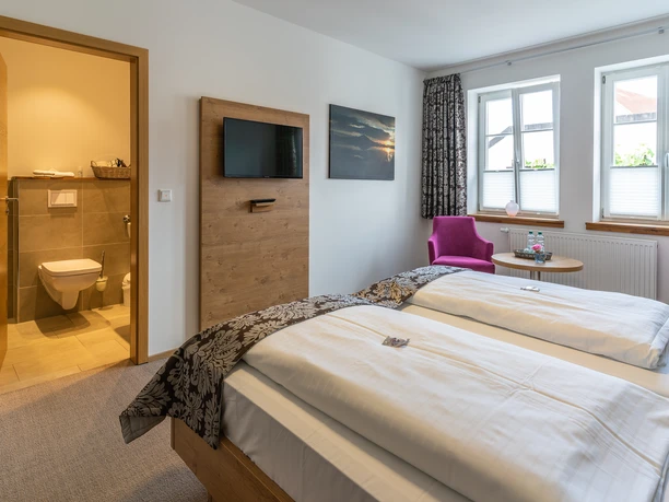 Doppelzimmer Modernes Doppelzimmer mit zwei weißen Betten, Flachbild-TV und angrenzendem Badezimmer.