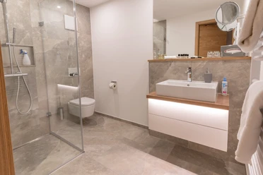 Modernes Badezimmer mit Dusche, Toilette, Waschbecken und minimalistischem Design in neutralen Tönen.
