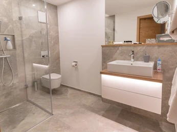 Modernes Badezimmer mit Dusche, Toilette, Waschbecken und minimalistischem Design in neutralen Tönen.