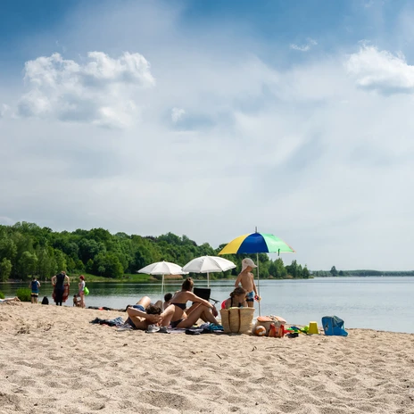 A family enjoying a day at the beach looks out over Lake Cospuden in the Leipzig New Lake District, leisure, family day out