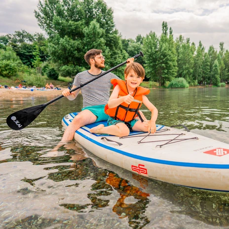 A father and son paddleboarding at Lake Cospuden in the summer, lake swimming, leisure, family