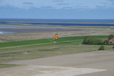 Pilsumer Leuchtturm aus der Luft Roter und gelber Leuchtturm steht auf grünem Deich, von oben mit Blick auf Küste und Meer fotografiert.