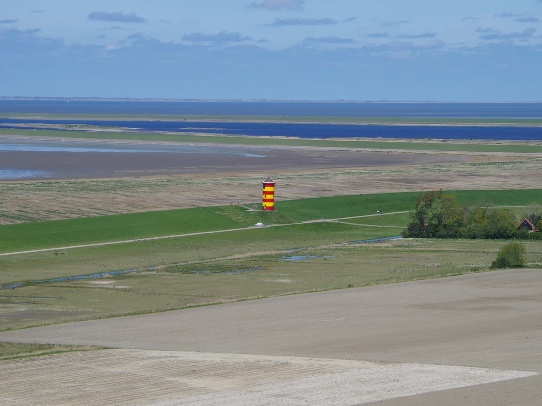 Pilsumer Leuchtturm aus der Luft Roter und gelber Leuchtturm steht auf grünem Deich, von oben mit Blick auf Küste und Meer fotografiert.