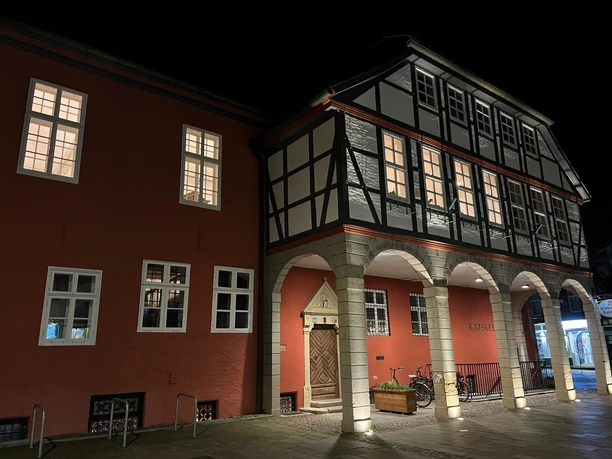 Rathaus Nienburg Half-timbered town hall Nienburg at night, illuminated, with arcades and red facades, next to bicycle.