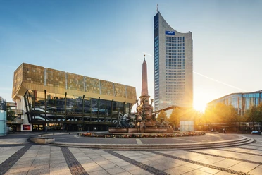 Pohled na Gewandhaus v Lipsku, Mendovu fontánu a mrakodrap City na náměstí Augustusplatz při západu slunce, památky, hudba, kultura – představuje Leipzig Convention Bureau
