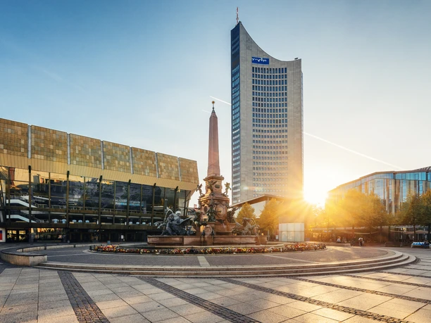 Pohled na Gewandhaus v Lipsku, Mendovu fontánu a mrakodrap City na náměstí Augustusplatz při západu slunce, památky, hudba, kultura – představuje Leipzig Convention Bureau