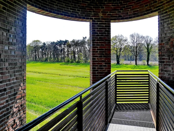 Landschaftsfenster Wemkendorf.JPG Blick durch einen Ziegelbogen auf grüne Wiesen und Bäume. Holzgeländer im Vordergrund.