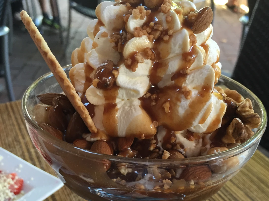 Ein Eisbecher mit Sahne, knackigen Nüssen, knuspriger Waffelrolle und süßem Karamellsirup.A sundae with cream, crunchy nuts, crispy wafer roll and sweet caramel syrup.En sundae med creme, knasende nødder, sprød vaffelrulle og sød karamelsirup.Een sundae met room, knapperige noten, knapperig wafelbroodje en zoete karamelsiroop.