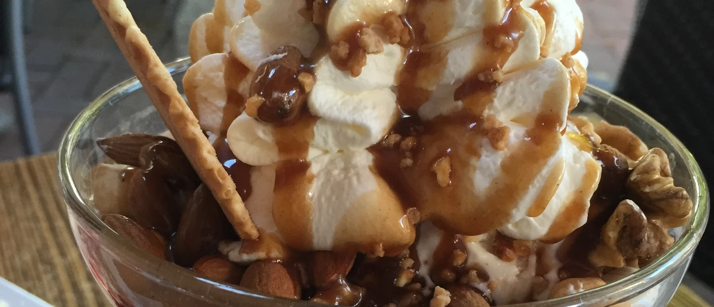 A sundae with cream, crunchy nuts, crispy wafer roll and sweet caramel syrup.