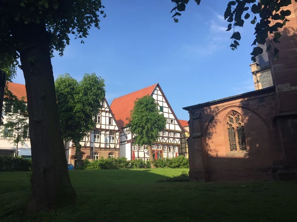 Hotel Alt Warburg Fachwerkfassade eines historischen Gebäudes in Warburg, umgeben von Bäumen und grüner Wiese.