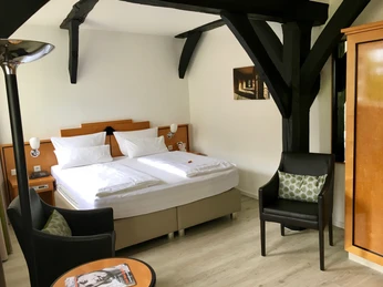 Hotel Alt Warburg - Doppelzimmer Komfort Zwei Einzelbetten nebeneinander in einem hellen Zimmer mit Holzdetails und Sitzgelegenheiten.