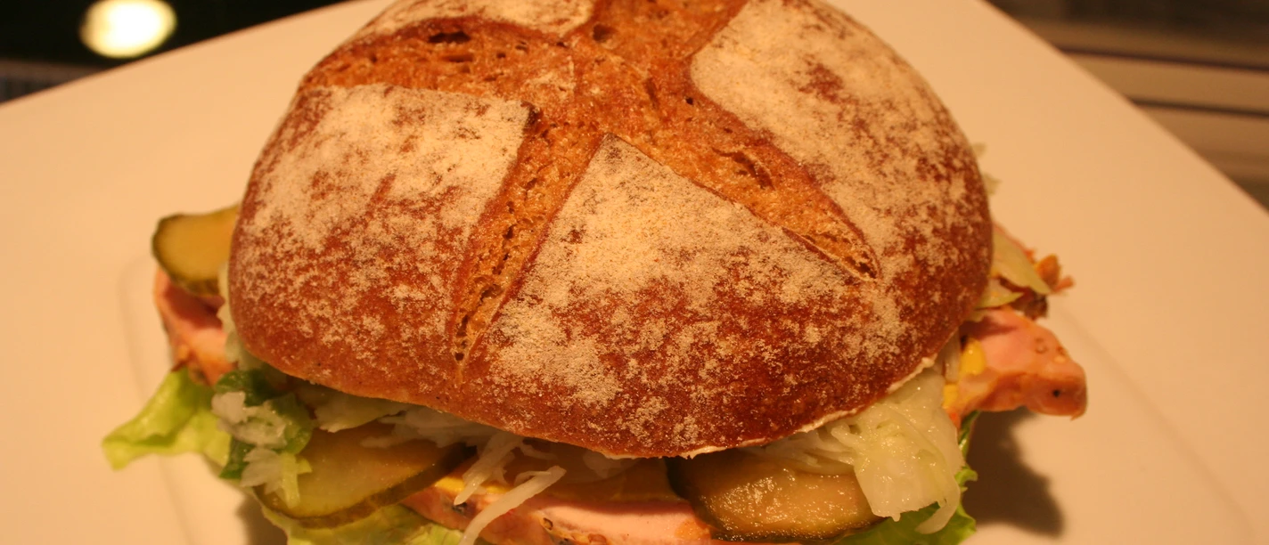 Belegtes Brötchen Roggenbrötchen belegt mit Salat, saftigem Bratenaufschnitt, frischen Gurkenscheiben und Krautsalat.