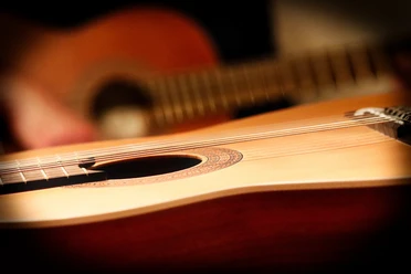Gitarre Nahaufnahme einer klassischen Akustikgitarre, mit Fokus auf den Korpus und die Saiten.