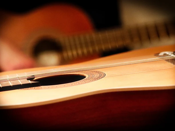 Gitarre Nahaufnahme einer klassischen Akustikgitarre, mit Fokus auf den Korpus und die Saiten.