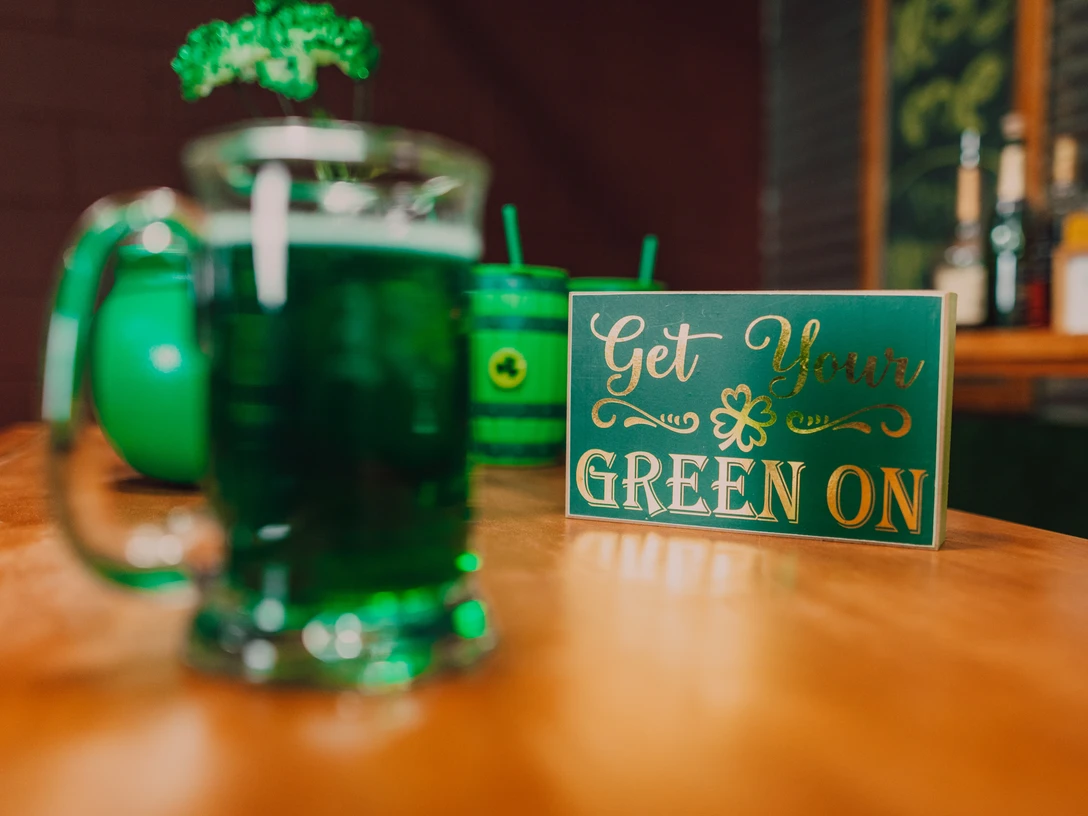 Irish Folk Abend Ein Glas mit grünem Getränk auf einem Tisch, daneben ein Schild mit dem Spruch "Get Your Green On".