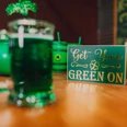 Irish Folk Abend Ein Glas mit grünem Getränk auf einem Tisch, daneben ein Schild mit dem Spruch "Get Your Green On".