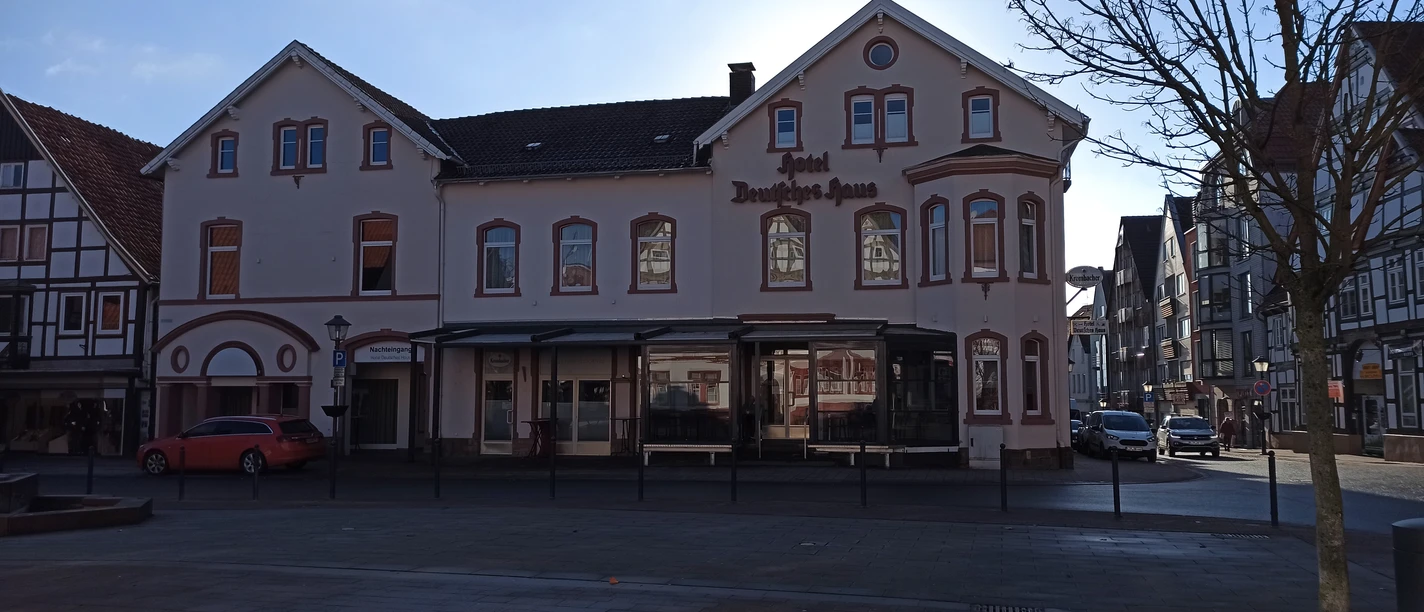 Fassade des Hotels Deutsches Haus in einer modernen, zweigeschossigen Struktur mit Erker und Gauben.