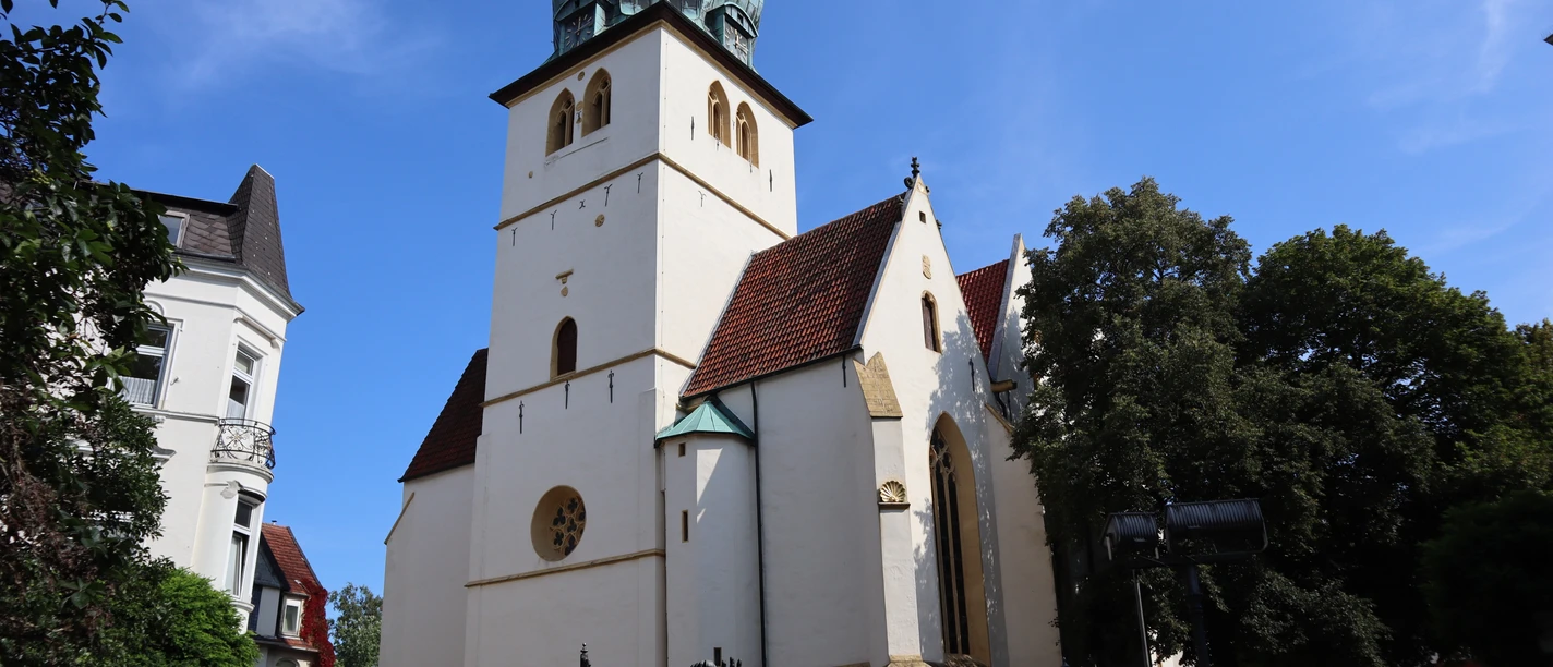 Gotische Jakobi-Kirche in Stadthegendorf mit markantem grünen Turm, umgeben von Bäumen und Gebäuden.