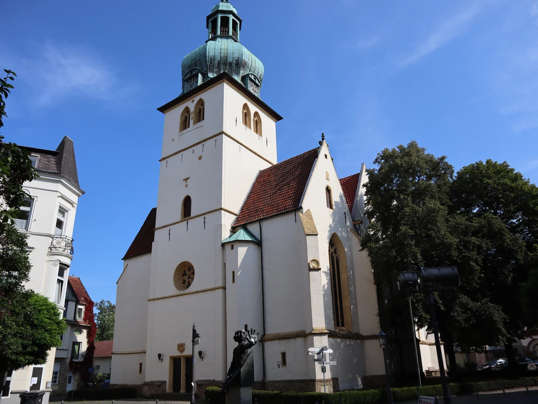 Jakobi-Kirche (3).JPG Gotische Jakobi-Kirche in Stadthegendorf mit markantem grünen Turm, umgeben von Bäumen und Gebäuden.