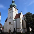 Jakobi-Kirche (3).JPG Gotische Jakobi-Kirche in Stadthegendorf mit markantem grünen Turm, umgeben von Bäumen und Gebäuden.