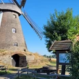 Windmühle Südhemmern Historische Windmühle Südhemmern, umgeben von grünem Land, blauer Himmel und Rastplatz mit Info-Tafel.