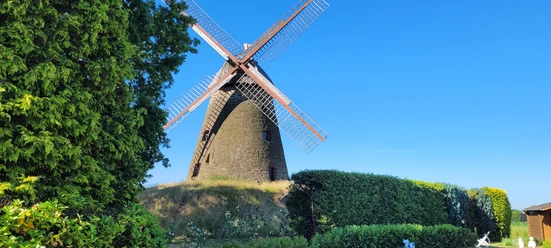 Windmühle Nordhemmern Historische Windmühle Nordhemmern mit großen Flügeln, umgeben von grünen Bäumen und Hecken.