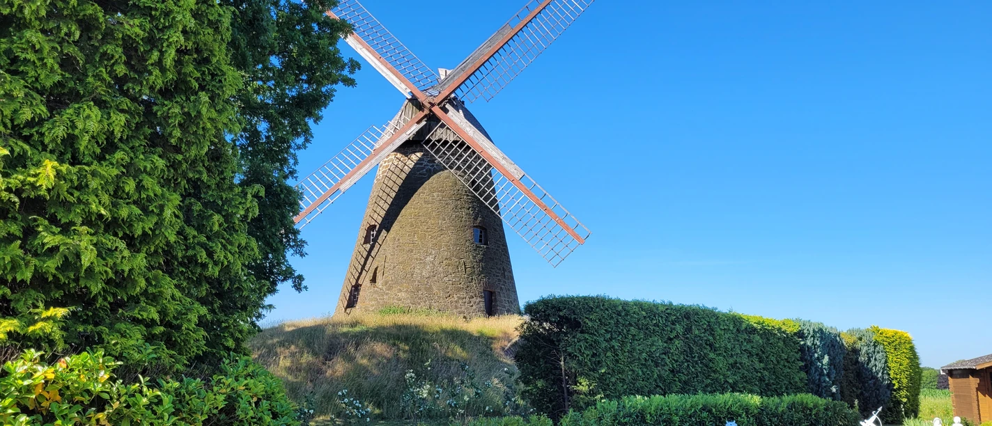 Windmühle Nordhemmern Historische Windmühle Nordhemmern mit großen Flügeln, umgeben von grünen Bäumen und Hecken.