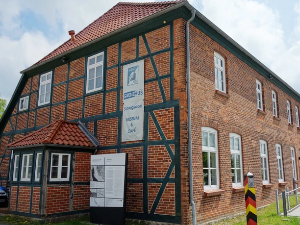 Grenzhus Schlagsdorf (J.Trebesius).JPG Fassade des Grenzhus Schlagsdorf aus Backstein mit einem historischen Grenzstein davor