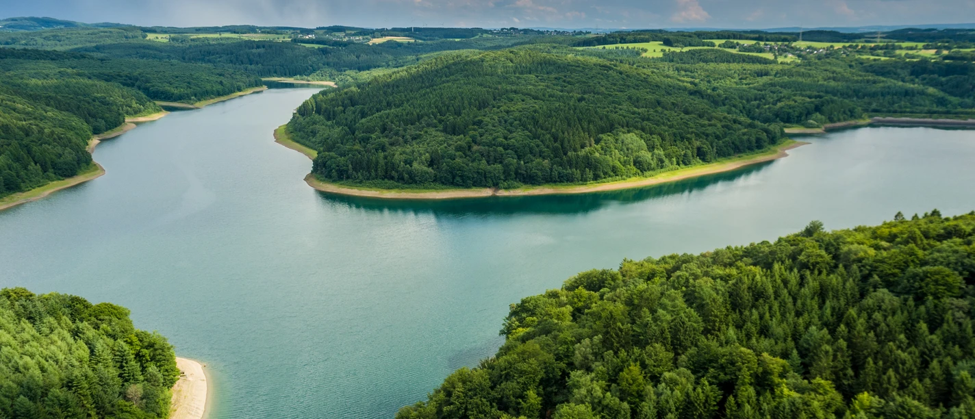Wiehltalsperre Ein ruhiger See inmitten grüner Hügel und Wälder unter einem bewölkten Himmel in der Region Wiehl.