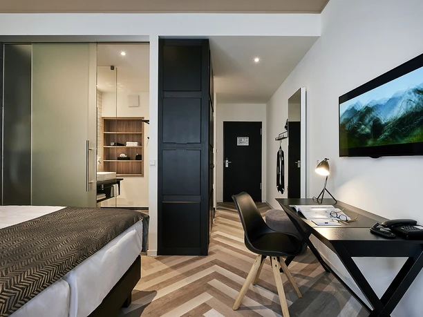 Zimmer © Hotel Hansa.jpg Modernes Hotelzimmer mit Doppelbett, Schreibtisch, flachem Fernseher und stylischem Badbereich.