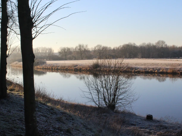 Wintermorgen an der Weser mit vereisten Bäumen und ruhigem Wasser, eingefangen bei Sonnenaufgang.