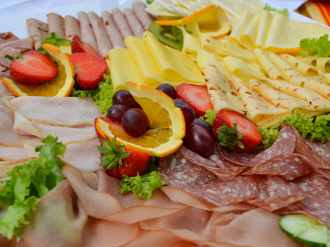 Fruehstueck_SHS_CC-BY-SA_Teutoburger_Wald_Stadt_Schloss_Holte-Stukenbrock (3).jpg Vielfältige Frühstücksplatte mit Aufschnitt, Käse, frischen Erdbeeren, Orangenscheiben und Trauben.