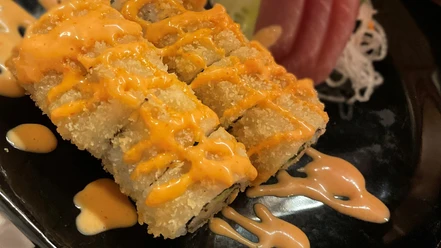 Sushi Tempura_CCBYSA_Teutoburger Wald_Stadt Schloss Holte-Stukenbrock-10.jpg Sushi-Tempura-Gericht auf schwarzem Teller mit knusprigem Teig und würziger Soße garniert.