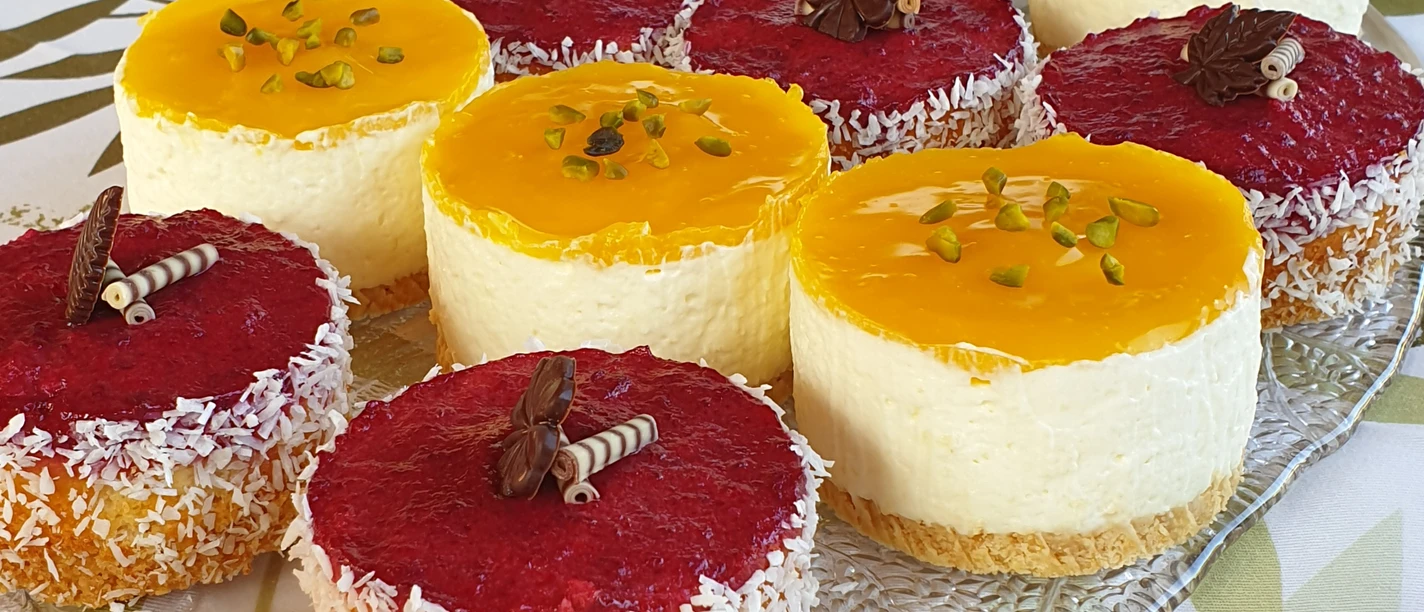 Eine Auswahl an bunten Mini-Törtchen mit Fruchtbelag und Schokoladendeko auf einem Glastablett.