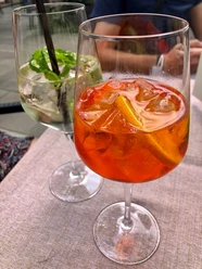 Zwei erfrischende Cocktails in großen Gläsern stehen auf einem Tisch, jeweils mit Eis und Garnitur.