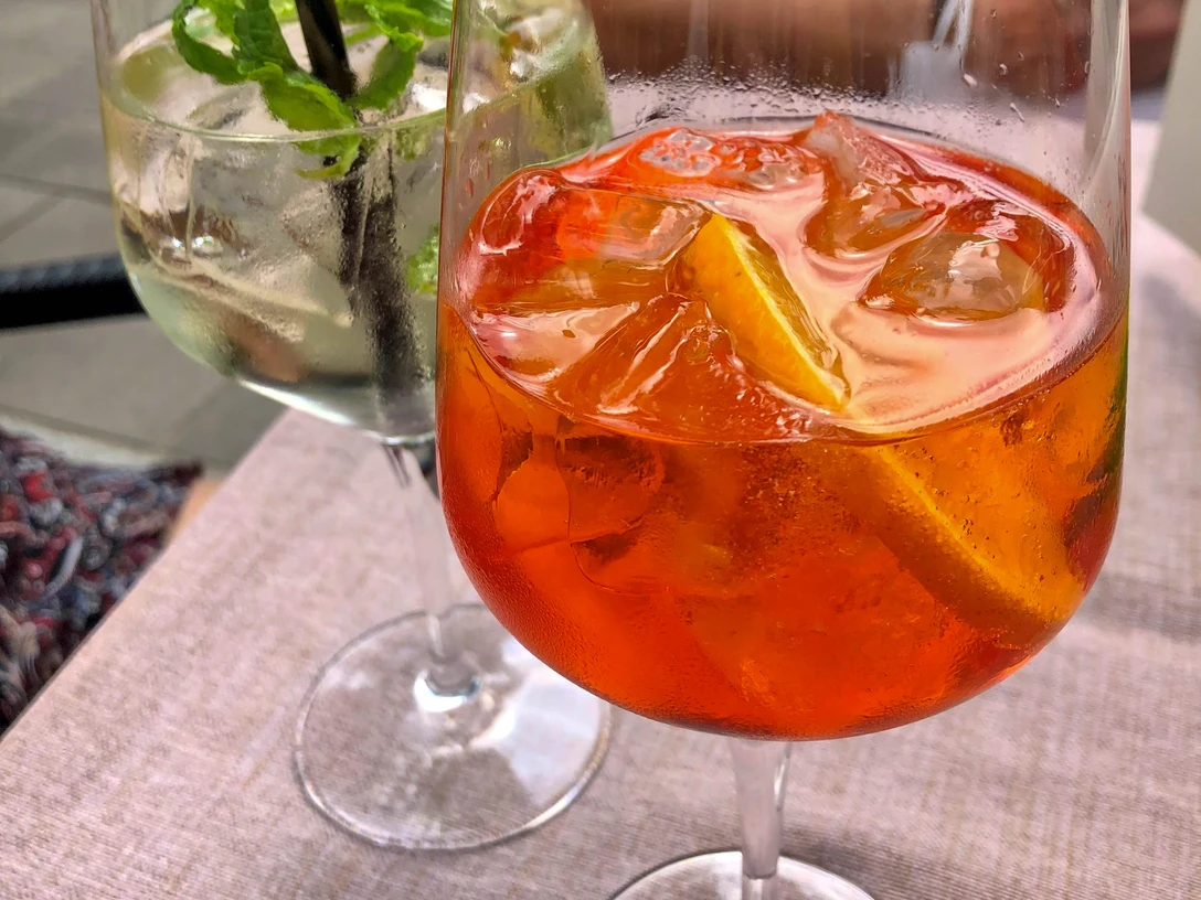 Zwei erfrischende Cocktails in großen Gläsern stehen auf einem Tisch, jeweils mit Eis und Garnitur.