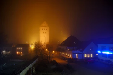 stmichealnebel.jpg St. Michael im Abendnebel: Beleuchteter Kirchturm ragt aus nebelverschleiertem Ortskern hervor.