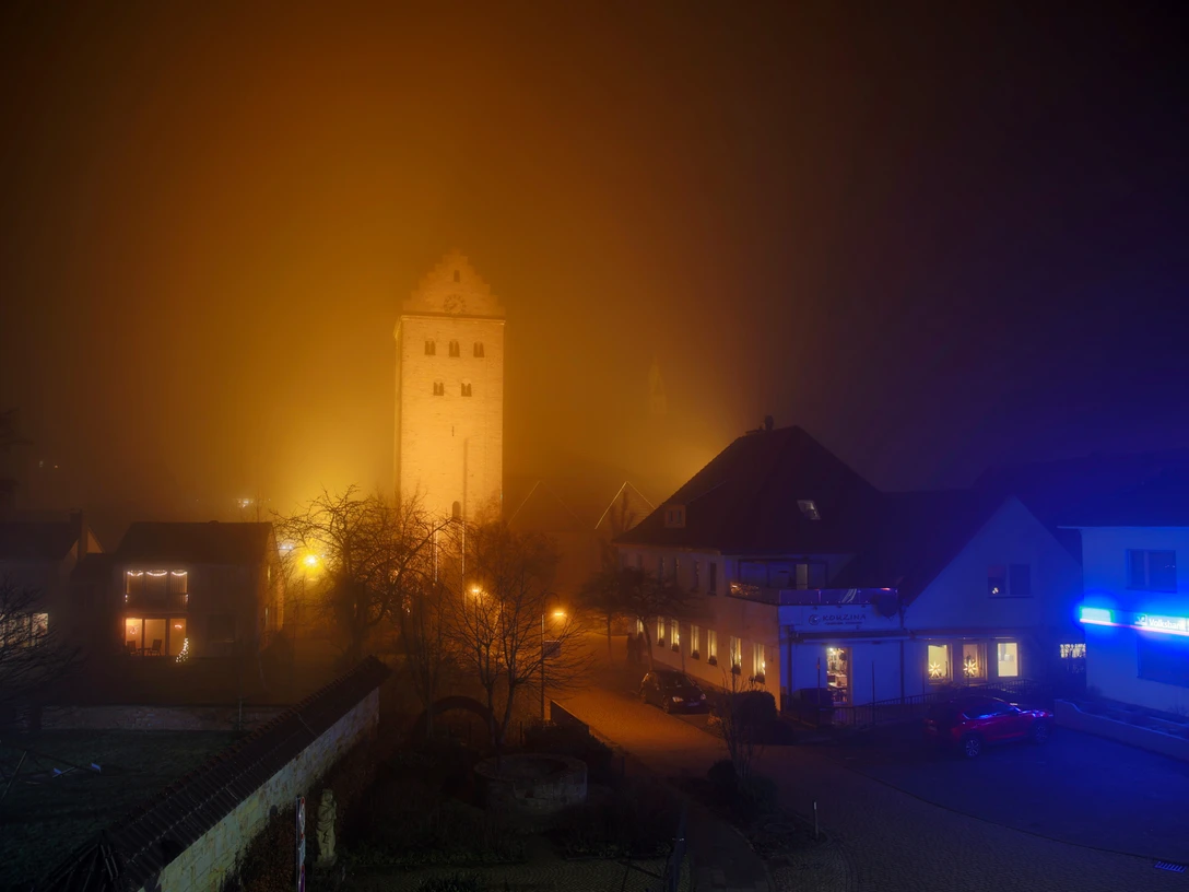 stmichealnebel.jpg St. Michael im Abendnebel: Beleuchteter Kirchturm ragt aus nebelverschleiertem Ortskern hervor.
