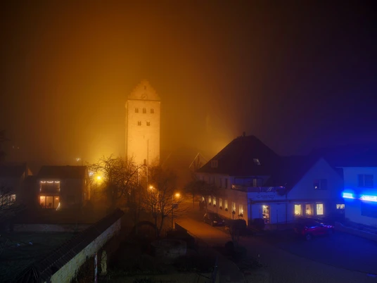 stmichealnebel.jpg St. Michael im Abendnebel: Beleuchteter Kirchturm ragt aus nebelverschleiertem Ortskern hervor.