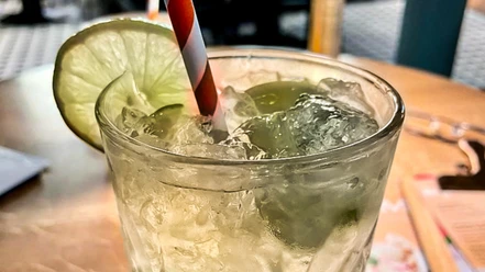 Limonade_CCBYSA_Teutoburger Wald_Stadt Schloss Holte-Stukenbrock-16.jpg Erfrischende limonadengrüne Getränkeglas mit Eiswürfeln, Limettenscheibe und gestreiftem Strohhalm.